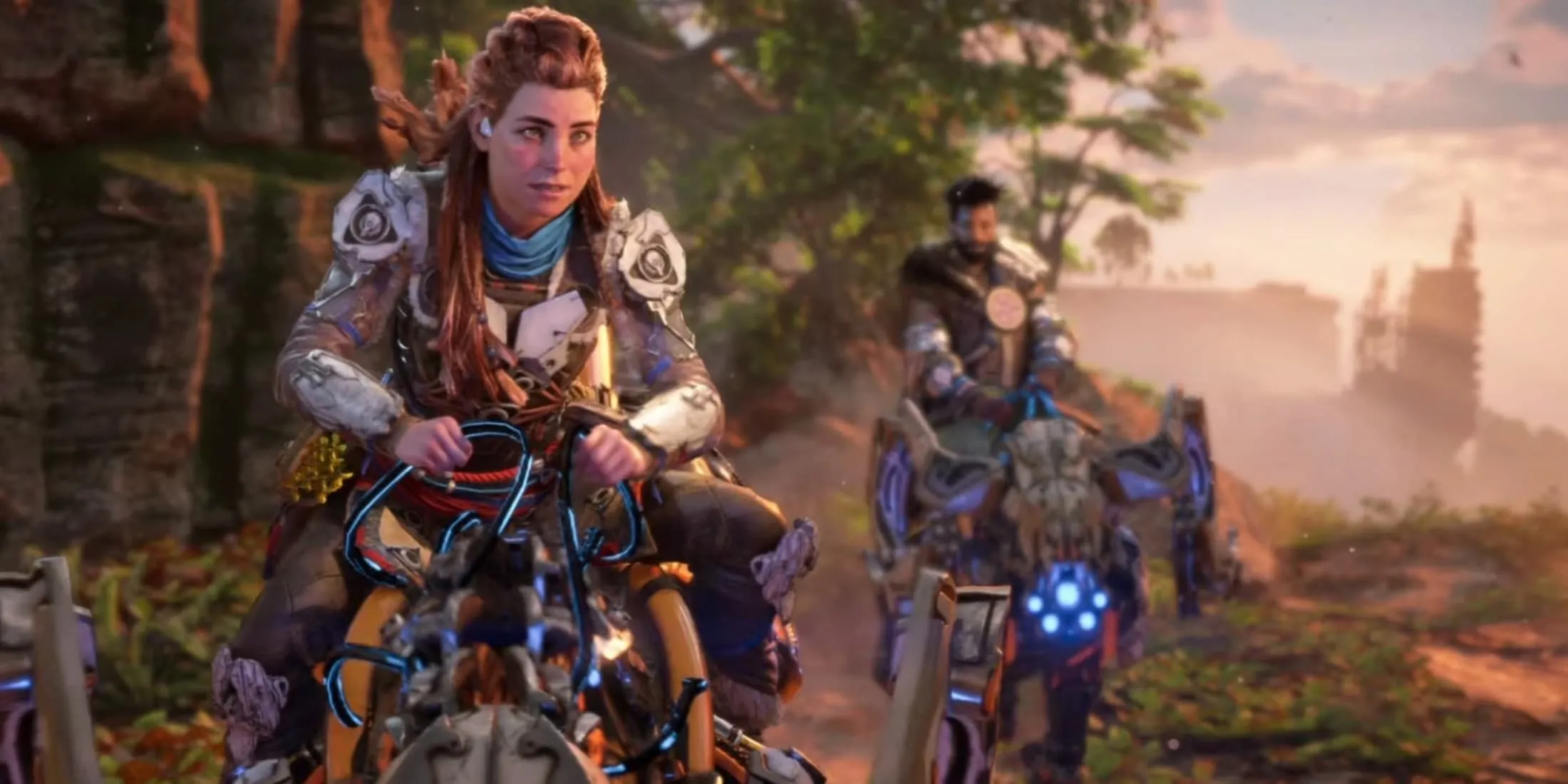 Aloy cưỡi thú máy cùng một nhân vật khác ở hậu cảnh trong Horizon Forbidden West, một game RPG hành động thế giới mở đồ họa đỉnh cao.