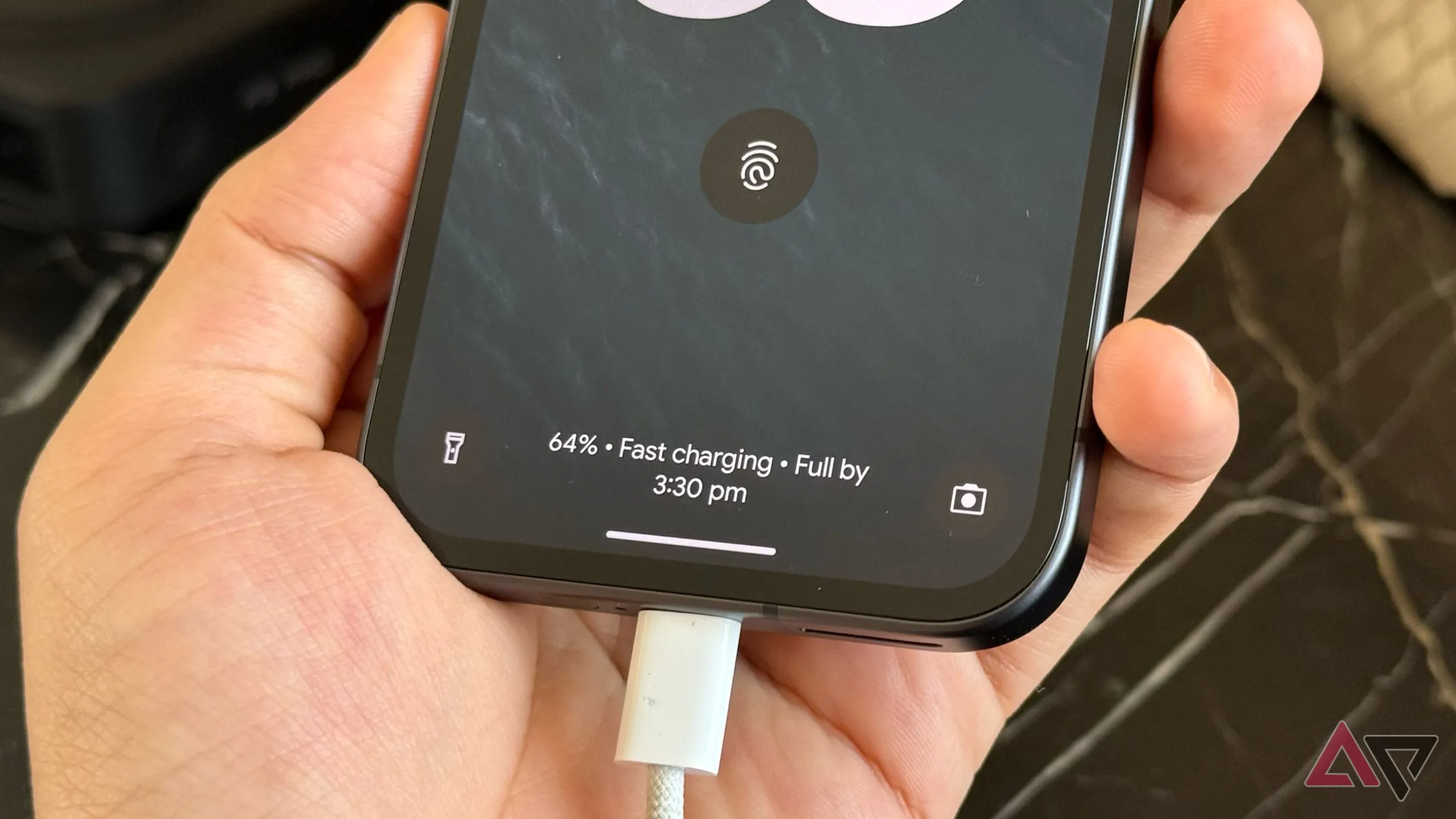 Pixel 9a đang sạc, nhắc nhớ việc đặt điện thoại lên dock/ổ sạc để giảm thời gian cầm máy.